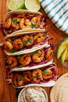 shrimp tacos with guacamole and lime wedges on a wooden table