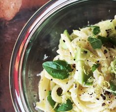 a glass bowl filled with pasta and vegetables