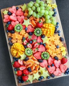 a wooden cutting board topped with cut up fruits and veggies on top of it