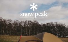 a tent pitched up in the grass with snow peak written above it