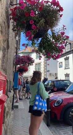 a woman is walking down the street with flowers hanging over her head