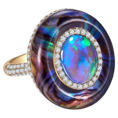 A 2.27 ct Solid Opal, Abalone Shell, Crystal and Diamond in 18k Yellow Gold. The solid opal is surrounded by a circle of diamond pave, on the outer circle is where the abalone shell is. The abalone shell is cover by thick crystal giving the ring a dome-like design. US Ring Size 8 Main opal weight is 2.27 ct Total diamond weight is 0.678 ct The diamonds are approximately E/F in colour with VS clarity Luxury Opal Fusion Jewelry, Luxury Multicolor Cabochon Opal Ring, Luxury Ethiopian Opal Fine Jewelry, Luxury Oval Opal Ring For Anniversary, Luxury Opal Ring With Cabochon Cut, Luxury Opal Cabochon Rings, Luxury Yellow Gold Opal Ring, Luxury Polished Opal Ring, Oval Cabochon, Luxury Polished Opal Ring With Oval Cabochon