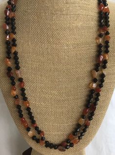 Featuring this pretty mix of orange carnelian semi-precious stones and black onyx or glass beads comprising this necklace.  It is a double strand and measures 25" in length.  The necklace is in very good vintage condition and has a silver tone hook clasp.  Each strand is 25" long so both strands do not lay totally flat.  Some of the carnelian stones fall in an abstract manner, see last picture. Black Carnelian Jewelry With Natural Stones, Handmade Black Carnelian Necklace, Orange Carnelian, Carnelian Stone, Hook Clasp, Necklace Vintage, Last Minute Gifts, Black Onyx, Semiprecious Stones