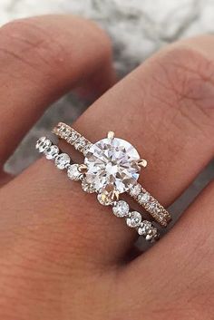 a woman's hand with two engagement rings on it and the ring is set in gold