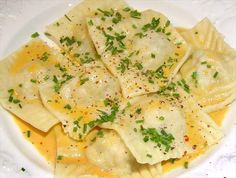 a white plate topped with ravioli covered in cheese and parsley on top of it