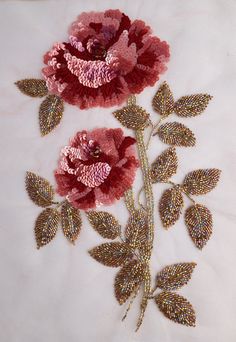 two pink flowers with green leaves on a white surface and gold sequins in the center