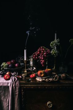 a table topped with fruit and candles on top of a wooden table covered in cloth