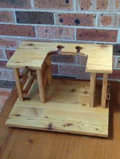 a small wooden desk and chair set on a wood floor in front of a brick wall