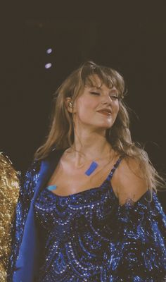 a woman in a blue dress standing on stage with her eyes closed and hands behind her back