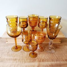 an assortment of wine glasses sitting on top of a wooden table next to each other