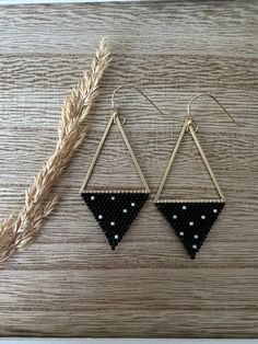 black and white triangle earrings with polka dots hanging from the side on a wooden surface