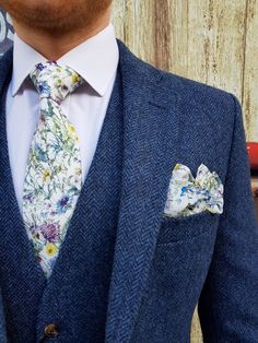 a man wearing a blue suit with floral print on the lapel and matching tie