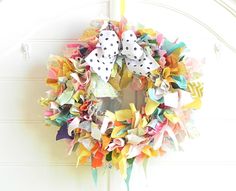 a colorful wreath hanging on the side of a white door with polka dots and bows