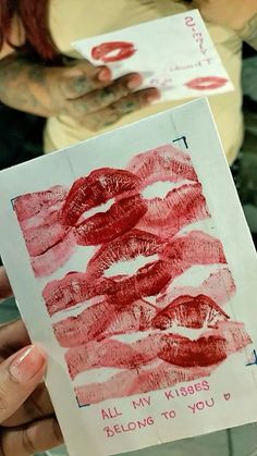 a person holding up a piece of paper with lipstick on it and writing all my kisses belong to you