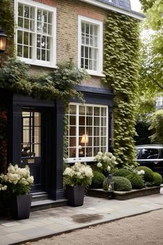 a building with many windows and plants on the side of it, along with a car parked in front