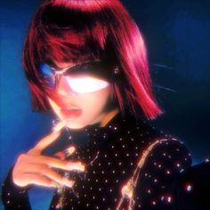 a woman with bright red hair and sunglasses on her face is looking at the camera