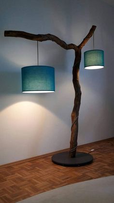 two lamps that are on top of a wooden tree branch in front of a wall