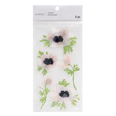 four white and black flowers with green leaves in the middle on a clear plastic bag