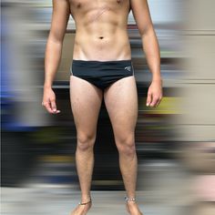 a man with no shirt standing on a surfboard in front of a blurry background