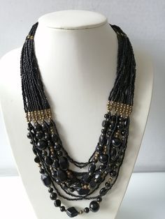 Multi Strand Black Beaded Necklace, Black Seed Black Large Beads, Statement Necklace, Unique Beadwork, Inserts of Brass Beads, Wedding Party Vintage chunky necklace features multi strands and different types of black beads, small and large.  It is perfect for a formal event, either a wedding or party,  Makes a great gift for Valentine's day or Mother's day.  This necklace is great condition. Please keep in mind that we try to give you the best description possible and list any imperfections or damages the item may have but with vintage items there may be age flaws or some imperfections that we did not notice at the time of listing. Thank you Always feel free to contact me if you are interested in an item but need more details or want to ask me a question I am always here to assist you. If Vintage Chunky Necklace, Beaded Necklace Black, Black Beaded Necklace, Large Beads, Black Choker Necklace, Blue Beaded Necklace, Braided Necklace, Friendship Jewelry, Brass Beads