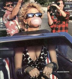 a woman in a polka dot dress is driving a car with two men behind her