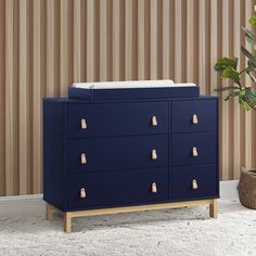 a blue dresser with gold handles and knobs in front of a striped wallpaper