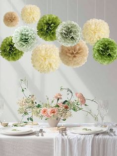 several paper flowers hanging from the ceiling above a table