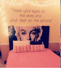 a bed with pink sheets and pillows in front of a sign that says keep your eyes on the stars and your feet on the ground