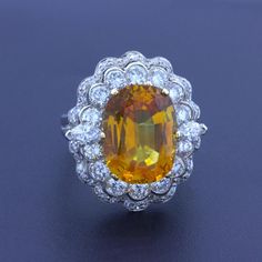 A large and impressive natural orange sapphire weighing 10.50 carats. It has a rich and brilliant orange color with excellent brightness. Additionally, it is extremely clean with no visible inclusions and certified by the GIA. It is complemented by 2.68 carats of round brilliant and marquise-shape diamonds set around the sapphire in a stylish pattern. Made in 14k white gold and ready to be worn.  Ring Size 6.75  Weight: 8.4 grams  Dimensions for this item are unknown. Please reach out with any q Fine Jewelry Orange Sapphire Anniversary Ring, Orange Sapphire Ring For Anniversary, Luxury Orange Yellow Sapphire Jewelry, Luxury Orange Jewelry With Yellow Sapphire, Orange Oval Sapphire Ring, Orange Oval Sapphire Gemstone Ring, Oval Orange Sapphire Ring, Orange Sapphire Ring For Formal Occasions, Marquise Shape Diamond