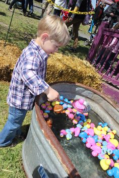 a young boy is playing in an old barrel filled with colorful candies on the grass