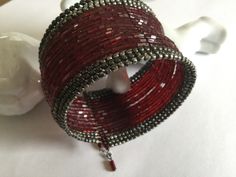 a red and silver beaded bracelet sitting on top of a table