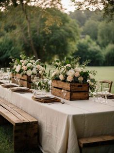 a long table with white flowers and greenery is set up for an outdoor dinner