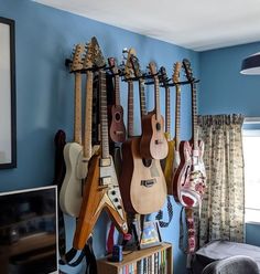 guitars are hanging on the wall in a room with blue walls and carpeted flooring