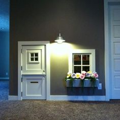 an open door leading into a room with flowers in the window box and light on