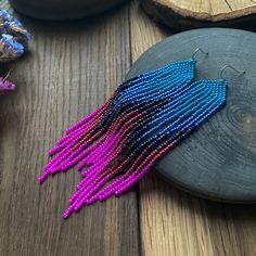 a pair of beaded earrings sitting on top of a wooden table next to other beads