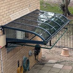 an enclosure attached to the side of a brick building next to a garden hose holder