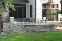 an outdoor patio with chairs and table next to a fenced in area that is surrounded by grass