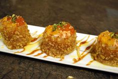 three desserts on a white plate with sauce drizzled over the top