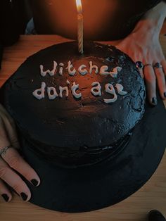 a woman holding a cake with the words witches don't age written on it