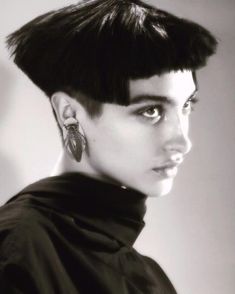 a black and white photo of a woman with short hair wearing earring's