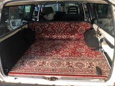 the back end of a van with an area rug on it's trunk and seats