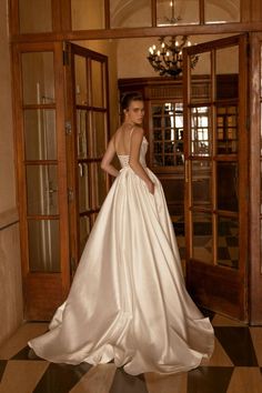 a woman in a wedding dress is standing by an open door