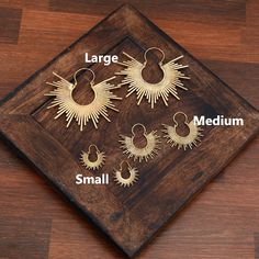 the different types of earrings are displayed on a wooden tray with text describing them as large, small, medium, and large