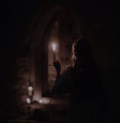 a woman holding a lit candle in the dark