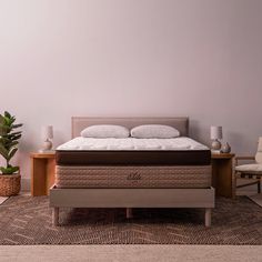 a bed with a mattress on top of it next to a chair and potted plant