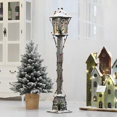 a small christmas tree is next to some miniature houses and a lamp post with lights on it