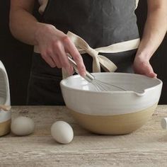 a person in an apron whisk eggs into a bowl