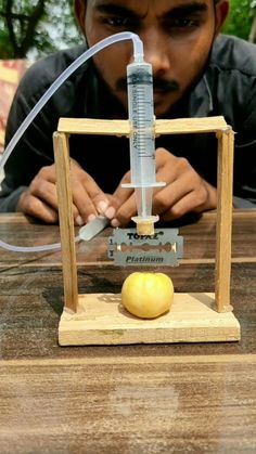 a man is looking at an apple with a syringe in front of him