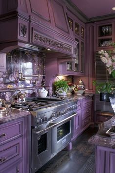 a kitchen with purple cabinets and an island in the middle is decorated with white flowers