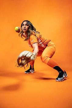 a woman in an orange uniform is holding a baseball